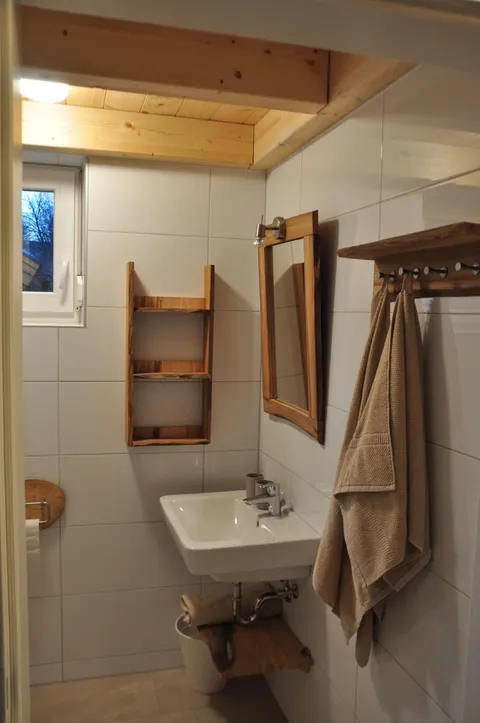 Waschbecken mit Holzspiegel im zweiten Badezimmer