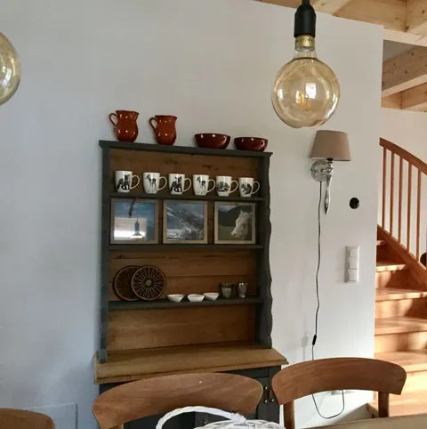 Holzkommode mit Geschirr und Fotos, Treppe im Hintergrund